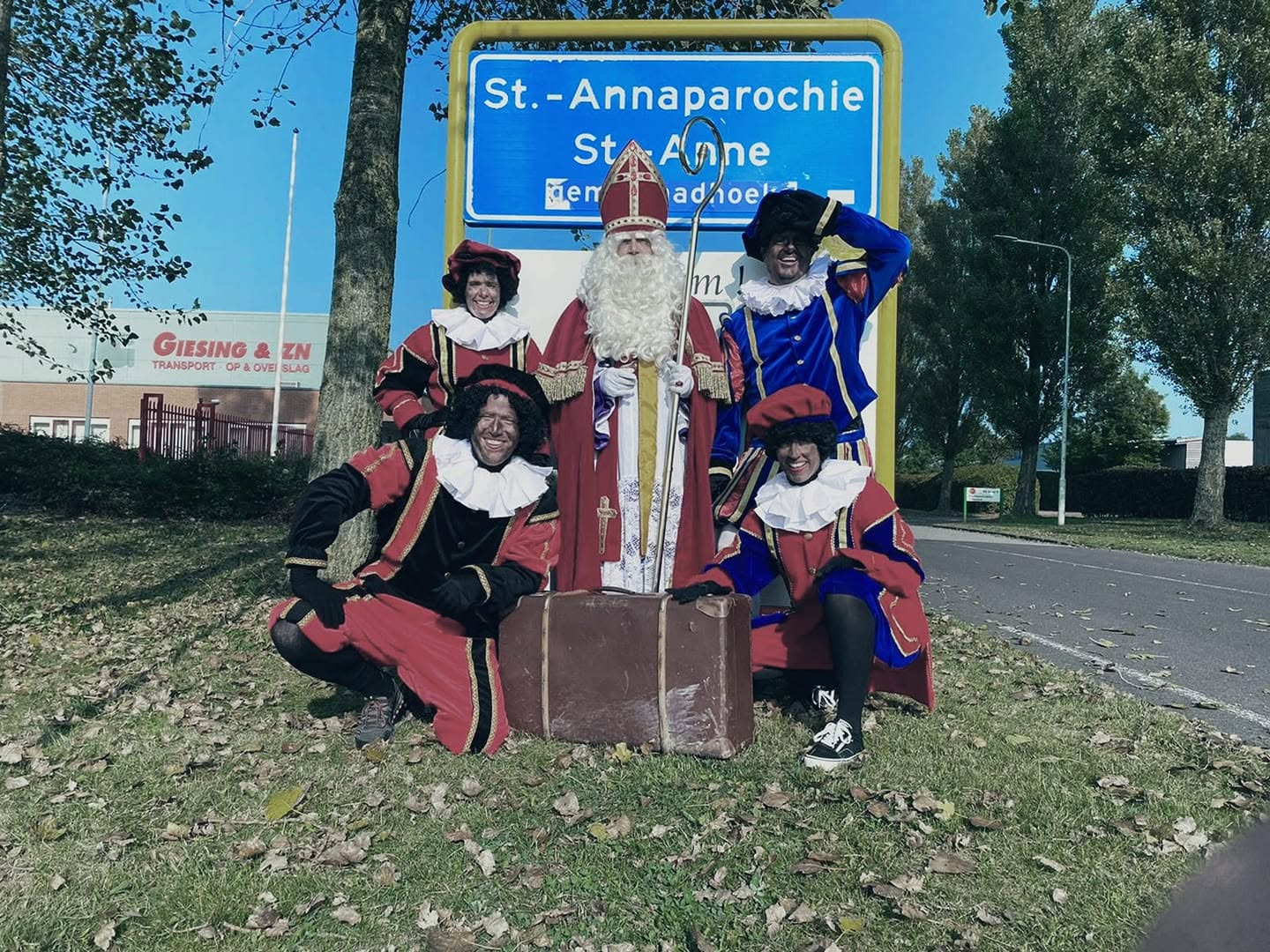 Sinterklaas en zijn gezelschap bij het plaatsnaambord van Sint Annaparochie