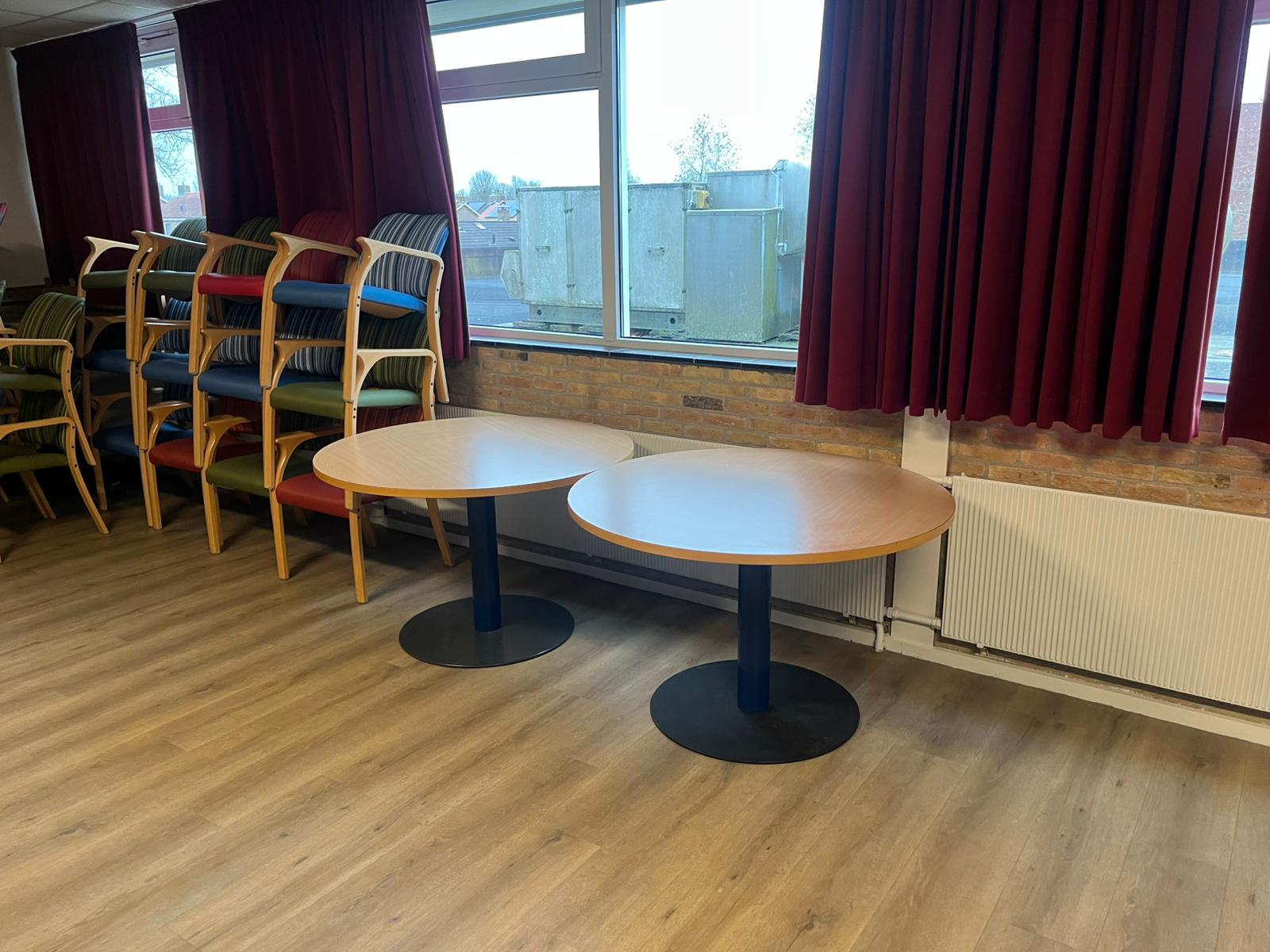 Een kijkje in Ons Huis: tafels en gestapelde stoelen bij het raam