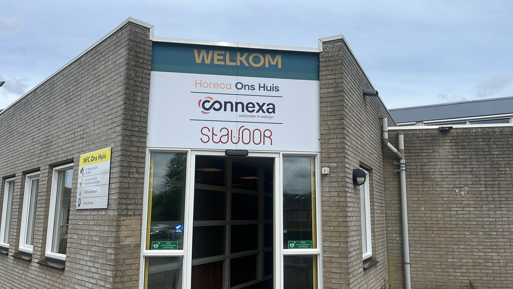 De ingang van Ons Huis met het welkomstbord